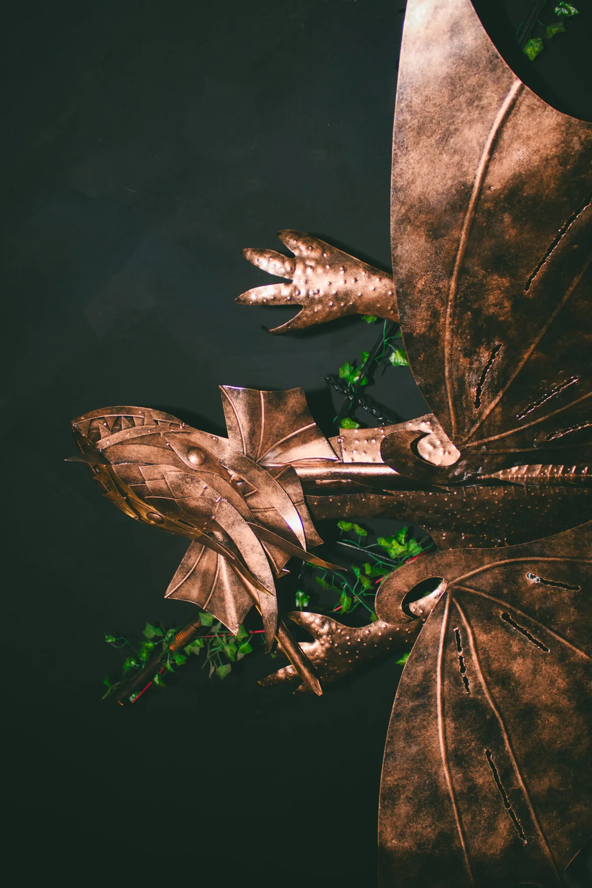 Dragón decorativo de metal entre hojas en Arcanum Domus