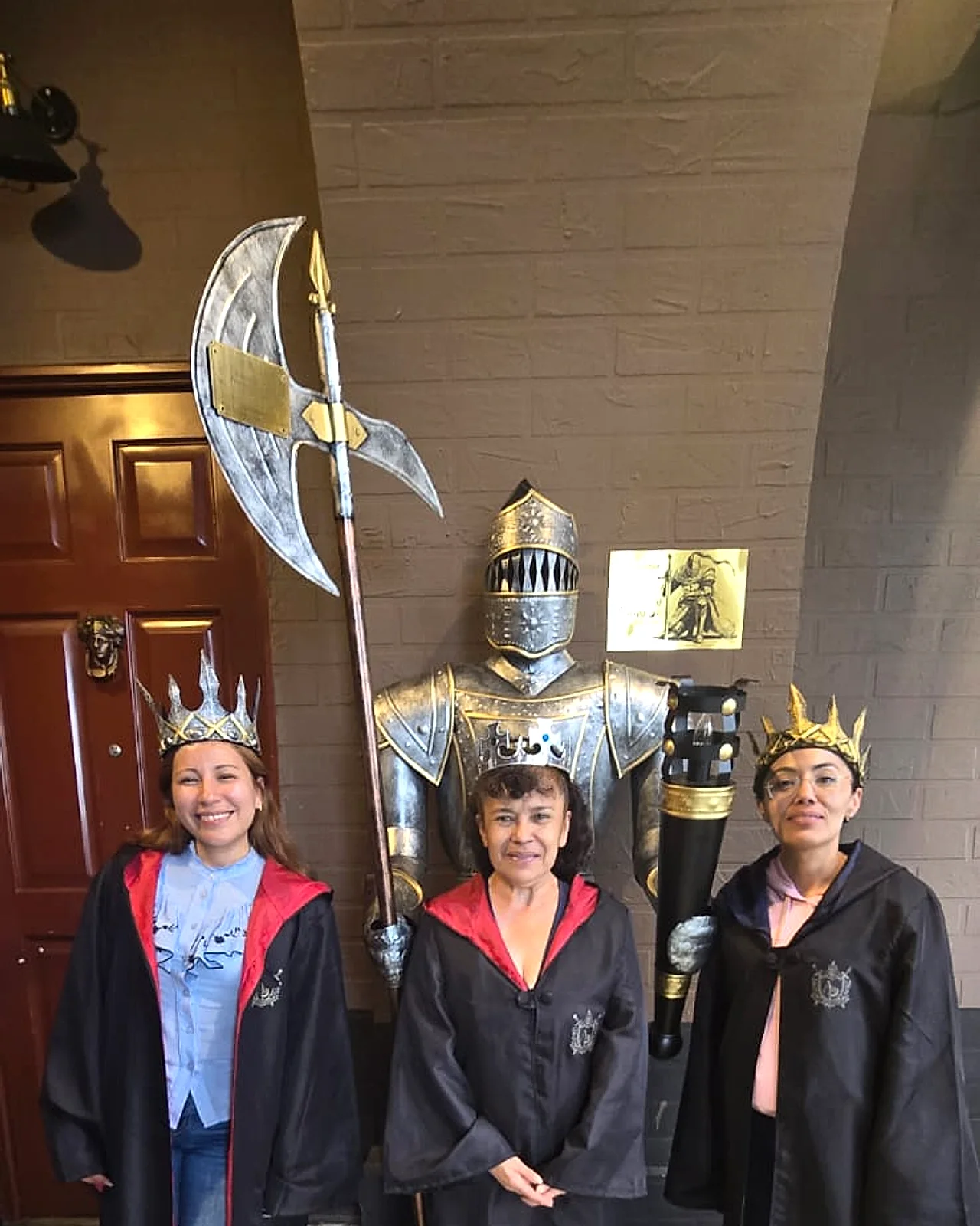 Familia con coronas posando junto a una armadura en Arcanum Domus