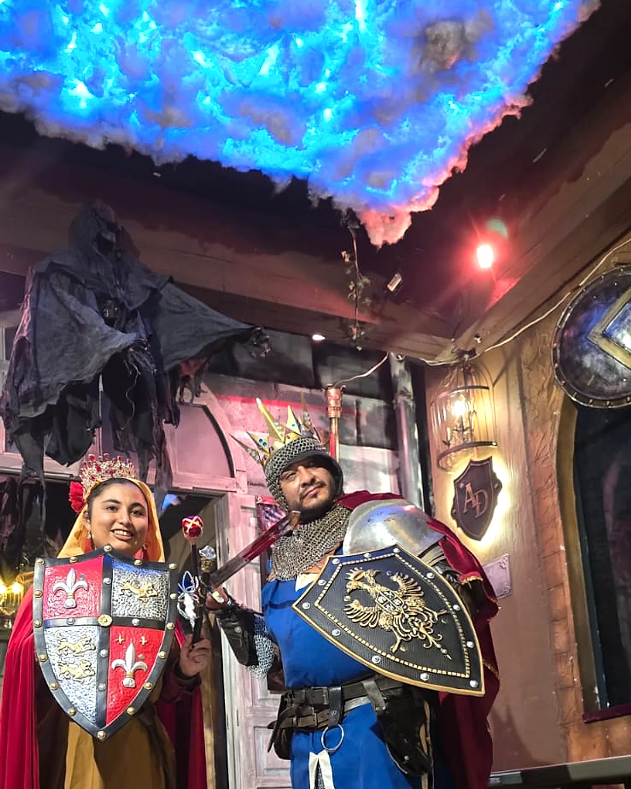 Pareja disfrazada de reina y caballero con escudos en Arcanum Domus