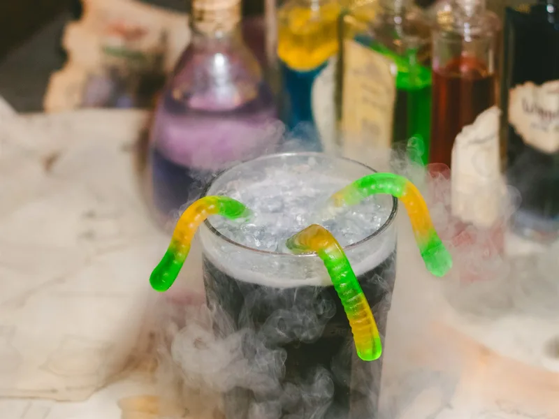 Elixir oscuro servido entre bruma fría con gomitas en Arcanum Domus